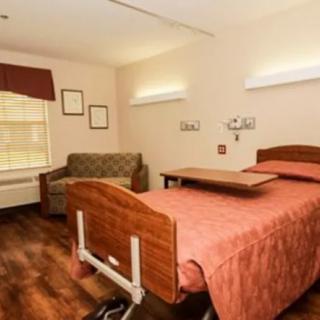 A clean and well-organized hospital room with a bed and seating area.