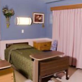A hospital room featuring a single bed, side table, and curtains.