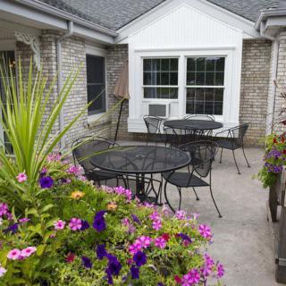 A cozy patio with tables and chairs surrounded by colorful flowers.