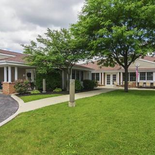 A school building with a grassy lawn and trees on a cloudy day.