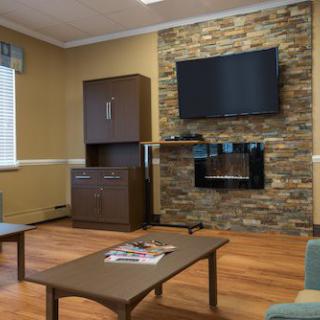 A modern living room featuring a stone accent wall with a mounted TV and fireplace, complemented by wooden flooring and sleek furniture.