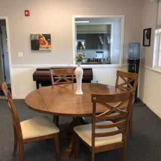A cozy dining area with a round wooden table and chairs, featuring a decorative vase in an office setting.