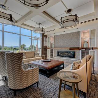 A modern living room with large windows, comfortable seating, and a stylish fireplace.