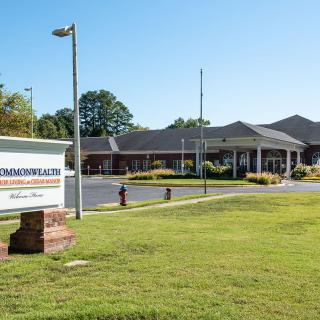 A healthcare facility with a sign and well-maintained lawn on a sunny day.