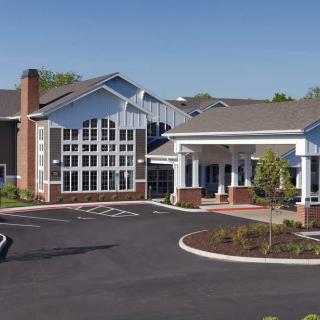 A modern residential building with a spacious entrance and landscaped parking area.