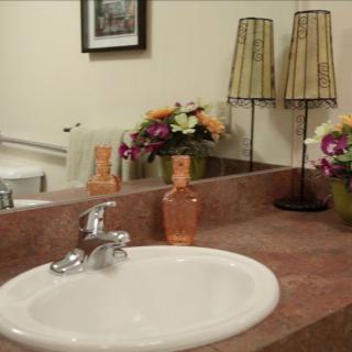 A neatly arranged bathroom sink with decorative elements including flowers and lamps.