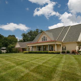 A charming residential house set against a beautiful blue sky with neatly trimmed landscaping.