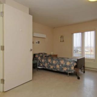An empty hospital room with a single bed and a window.