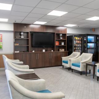 A modern waiting room with comfortable chairs, a television, and vending machines.