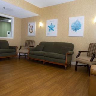 A cozy waiting room with sofas, chairs, and decorative artwork on the walls.