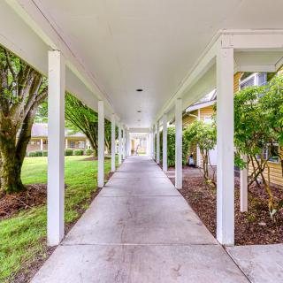 A covered outdoor walkway lined with columns and surrounded by lush greenery.