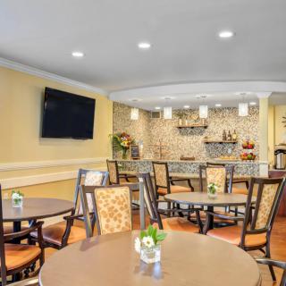 A cozy dining area with round tables and chairs, featuring a mounted television and stylish lighting.