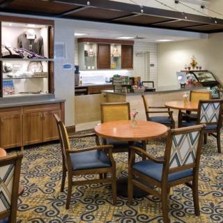 A cozy cafe interior with tables and chairs arranged on a patterned carpet.