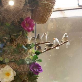 A group of birds perched on a branch surrounded by colorful flowers.