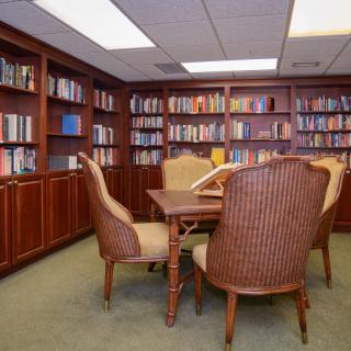 A cozy library corner with a table and chairs surrounded by bookshelves.