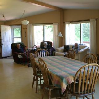 A cozy living room with a dining table and comfortable seating near large windows.