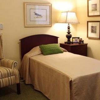 A cozy bedroom with a single bed, nightstand, and lamp.