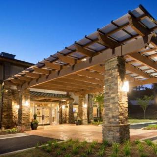 A beautifully lit building entrance with stone pillars and a wooden canopy during the evening.