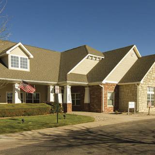 A suburban residential house with a brick exterior and an American flag displayed in the yard.