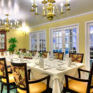 An elegant dining room with a formal table setting and chandeliers.
