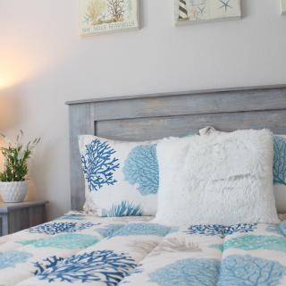 A cozy bedroom with blue and white bedding and decorative pillows.