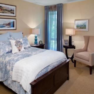 A cozy bedroom with elegant decor, featuring a bed, armchair, and two bedside lamps.