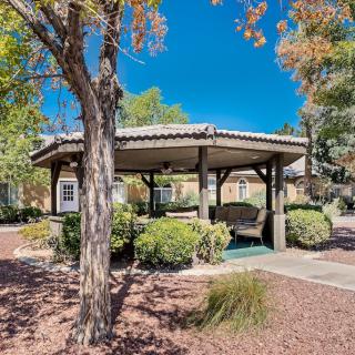 A serene park setting featuring a gazebo surrounded by trees and greenery on a sunny day.