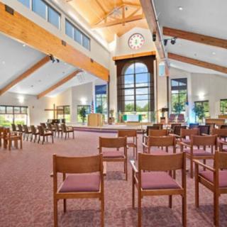 A spacious room with wooden beams, large windows, and neatly arranged chairs.