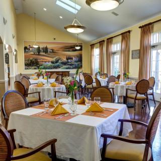 An elegantly arranged dining room with neatly set tables and chairs, featuring a warm ambiance.