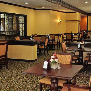 A cozy restaurant dining area with neatly arranged tables and chairs on a carpeted floor.