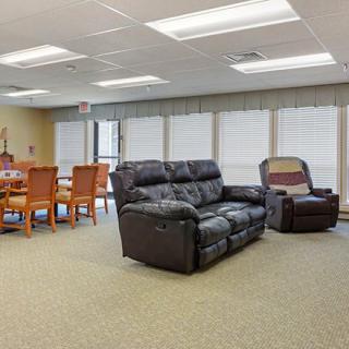 A cozy living room with a sofa, armchair, and dining table set.