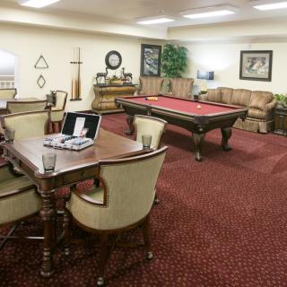 A cozy game room featuring a pool table and a seating area with a laptop on the table.