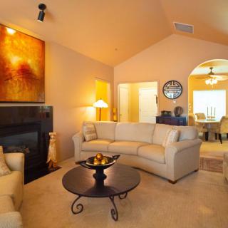 A cozy living room with comfortable sofas, a central coffee table, and warm lighting accentuated by artwork on the wall.