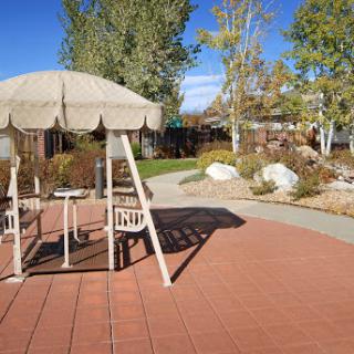 A serene park area featuring a shaded seating space and a winding pathway surrounded by greenery.