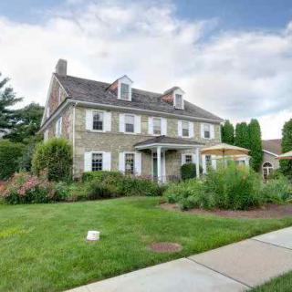 A colonial-style stone house with well-maintained landscaping and a manicured lawn.