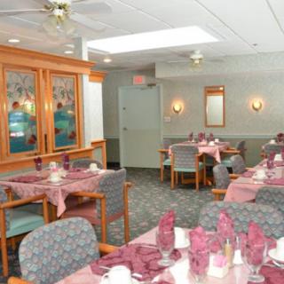A well-arranged dining area with neatly set tables and chairs, featuring folded napkins and soft lighting.