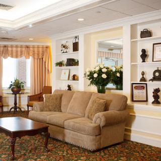 A cozy living room featuring a comfortable sofa, decorative shelves, and fresh flowers.