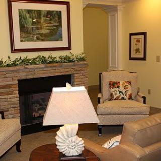 A cozy living room with a fireplace, armchairs, and decorative elements.