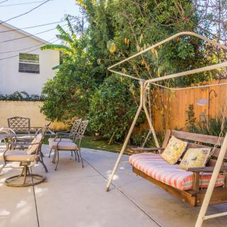 A cozy backyard with a swing and patio furniture surrounded by greenery.
