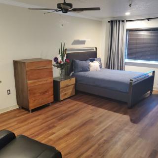 A modern minimalist bedroom with a wooden floor, featuring a bed and dresser.
