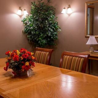 A cozy dining room with a wooden table, striped chairs, and decorative elements including flowers and a lamp.