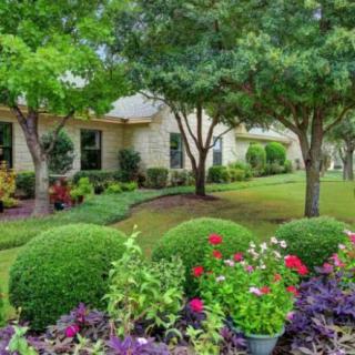 A beautifully landscaped garden with a variety of flowers and trees in front of a house.