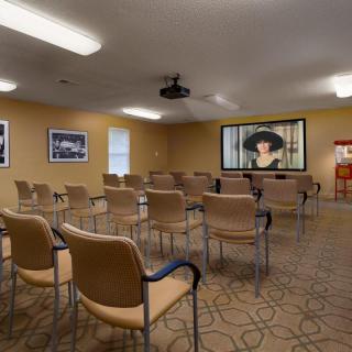 An empty conference room with chairs arranged in rows facing a projector screen.