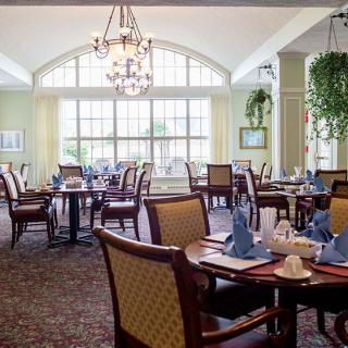 A well-appointed dining room with elegant table settings, large windows, and chandeliers.