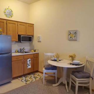 A cozy kitchen and dining area with a round table, chairs, refrigerator, and microwave.