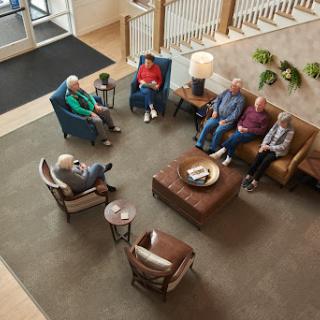 A group of seniors engaged in conversation in a comfortable lobby setting.