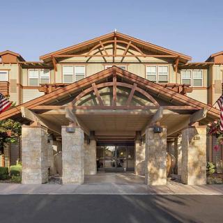 The entrance of a hotel adorned with flags and featuring a prominent wooden structure.