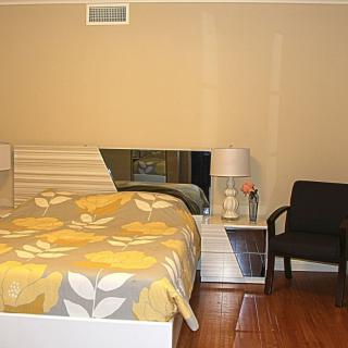 A cozy bedroom with a floral bedspread, bedside table, and a lamp.