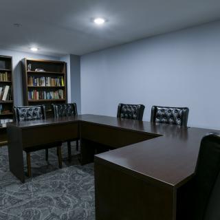 A conference room with a large table, chairs, and bookshelves.