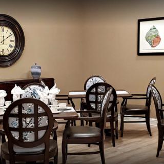A dining room with a set of elegant wooden chairs and table, featuring a wall clock and artwork.